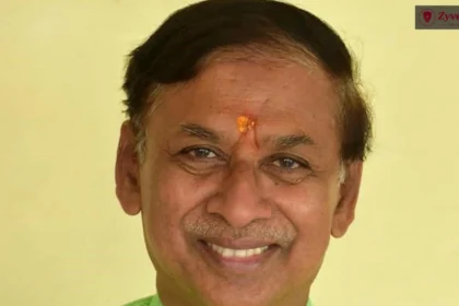 Close-up portrait of an Indian man with a tilak on his forehead, smiling and looking directly at the camera.
